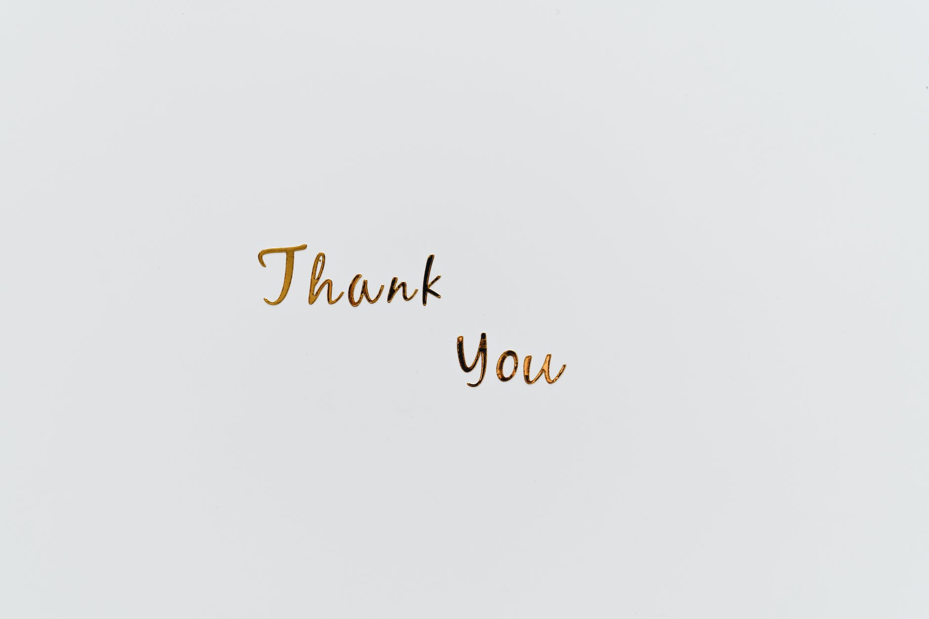 gold thank you text on a white surface